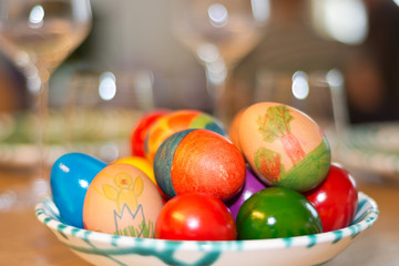 Easter eggs painted by children themselves in a fine porcelain from Austria on a table set with wine glasses. (wide aperture, low depth of field)