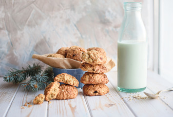 Appetizing and tasty oatmeal cookies with raisins and milk on a bright table.