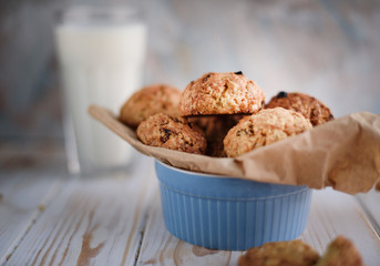 Appetizing and tasty oatmeal cookies with raisins and milk on a bright table.