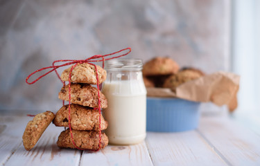 Appetizing and tasty oatmeal cookies with raisins and milk on a bright table.