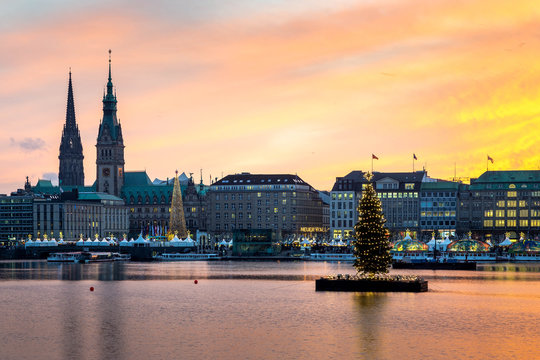 Sunset in Hamburg. Panoramic view of the decorated city center from Alster Lake, view to Hamburg Rathaus and a christmas tree installed in the center of the lake. Atmosphere before the New Year.