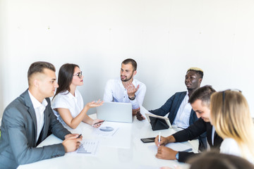 Successful team leader and business owner leading informal in-house business meeting. Businessman working on laptop in foreground. Business and entrepreneurship concept.