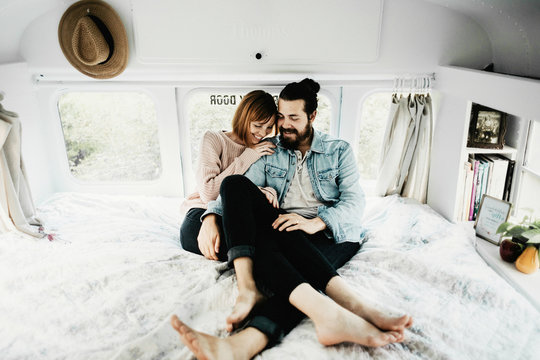 Cute hipster couple cuddling in converted school bus tiny home