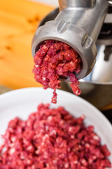 Raw meat coming out of the meat grinder as it is being minced.