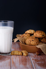 Appetizing and tasty oatmeal cookies with raisins and milk in a dark vein on the table