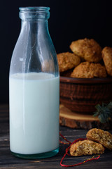Appetizing and tasty oatmeal cookies with raisins and milk in a dark vein on the table