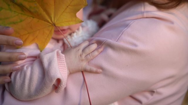 baby holds yellow leaf