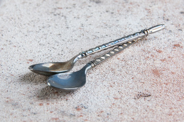 Two metal coffee spoons on concrete background.