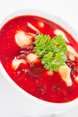 Traditional polish Christmas Eve dish: red borscht with uszka a mushroom filled kind of dumpling decorated with parsley 