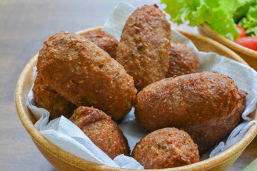 kibe - delicious brazilian salty on wooden table and accompanied by lemons and lettuce salad with tomatoes