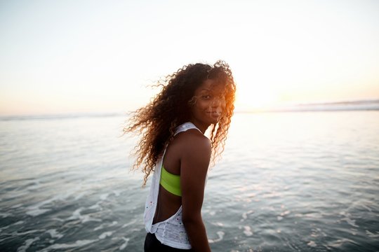 Fit, stylish woman enjoying sunset walk in ocean water