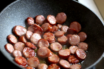 Sliced sausage frying in the pan. Selecttitve focus. 