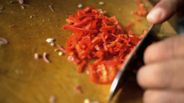 Asian chef preparing Basa gede chopping healthy raw vegetables on wooden cutting board in Balinese kitchen
