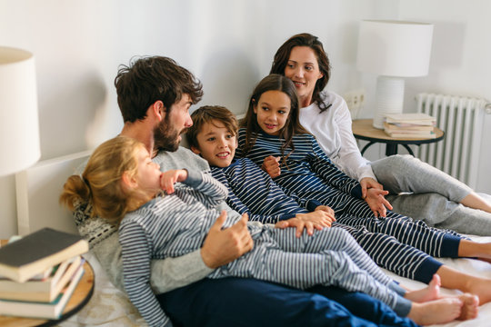 Family wearing pajama on bed. 