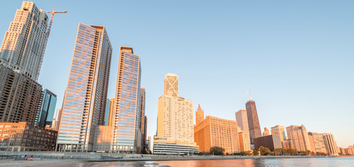 Chicago skylines along Lake Shore Drive reflection and working crane on building under construction from beach park at sunrise