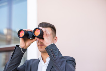 Fototapeta na wymiar American businessman using binoculars in office. Spy of competitors.