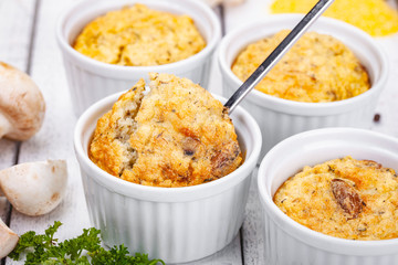 Polenta with mushrooms in white ramekin bowls on wooden rustic table. Close up
