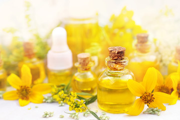 Essential oil bottles on medicinal flowers and herbs background, selective focus, toned