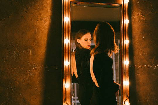 young androgyne man in the small black dress near the mirror
