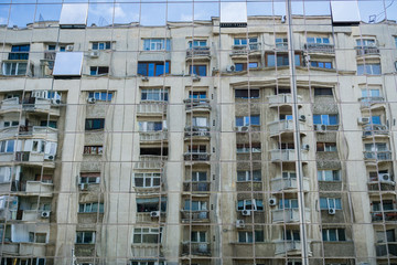 Fototapeta na wymiar Distorted view of apartment building reflected in the glass facade of an office tower, Bucharest, Romania