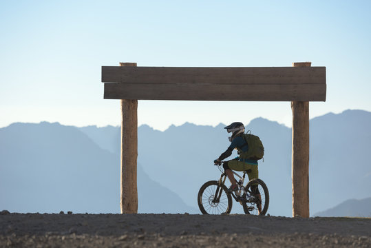 Mountain biker silhouette against desaturated mountain range 