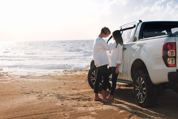 A young couple with a pick up truck on a deserted beach.young couple by pick-up truck parked on beach © pha88