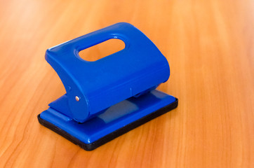 puncher on white background. dark blue hole punch on the table. stationery. office trivia