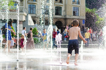 Kyiv, Ukraine - July 13, 2018: A family. summer time. children frolic in the fountain. splashing water. carelessness. happiness in small things