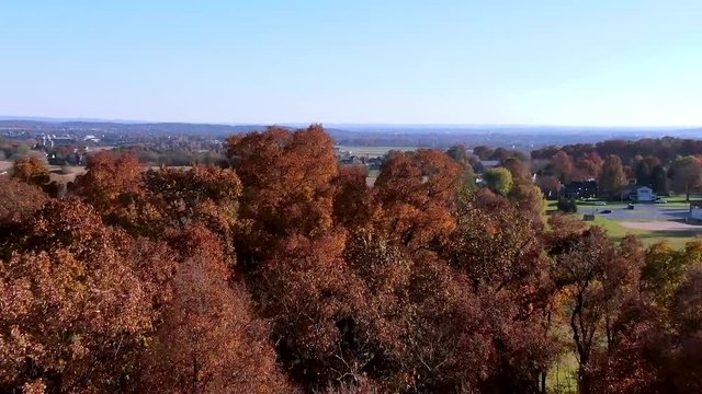Dolly zoom efect with drone flying above countryside, aerial view of country, rural landscape in eastern North America, forest in autumn foliage colors, vibrant red, brown and yellow