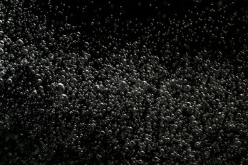 Black and white explosion of bubbles moving in water