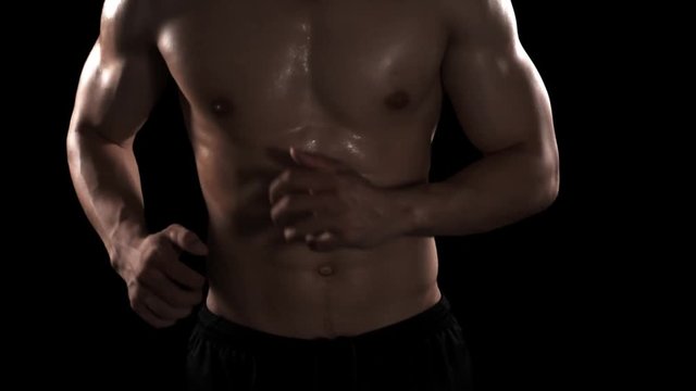 Young man with muscular body running on dark background in the studio