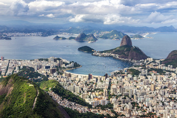 Views from Christ The Redeem mountain over Sugar Loaf, Rio do Janeiro city, suburbs and favelas, amazing views over the bays, islands, beach and the city skyline from the top on a cloudy day, Brazil
