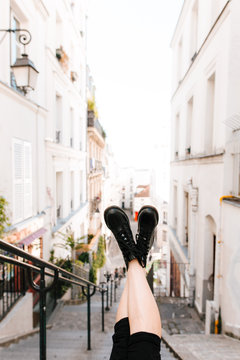 crossed legs wearing black boots with paris street background