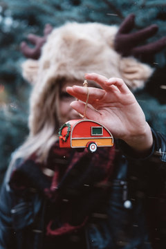 A women in her twenties decorating a tree in the snow at christmas time