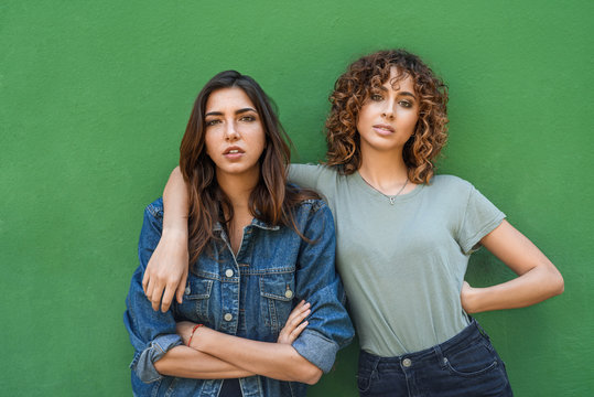 Stylish relaxed best friends over green background.