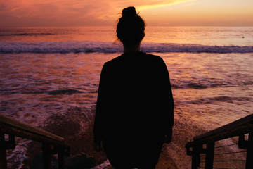 Silhouette of a woman enjoying a vibrant sunset. 