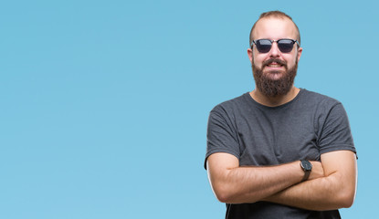 Young caucasian hipster man wearing sunglasses over isolated background happy face smiling with crossed arms looking at the camera. Positive person.