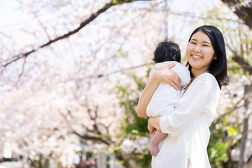 portrait of young asian mother and baby looking cherry blossom