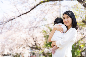 Fototapeta premium portrait of young asian mother and baby looking cherry blossom