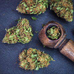 Marijuana buds up close with wooden pipe