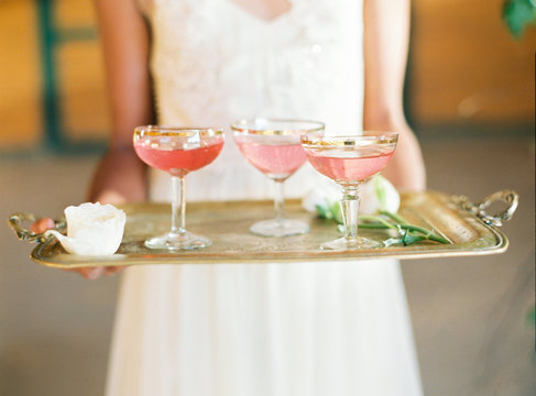 Fototapeta A vintage golden tray with 3 glasses of pink beverages 