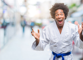 Afro american man wearing karate kimono over isolated background celebrating crazy and amazed for success with arms raised and open eyes screaming excited. Winner concept