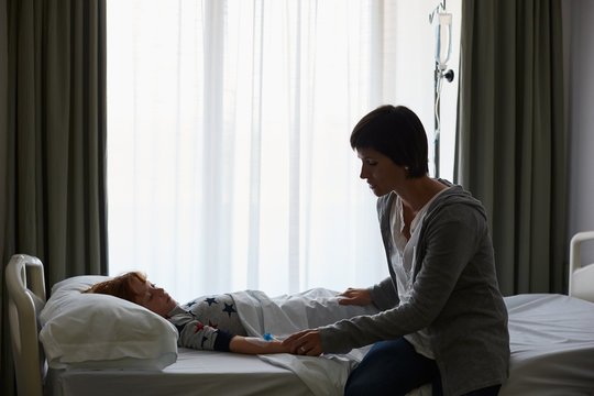 Silhouette of mother taking care of  child patient in a hospital room
