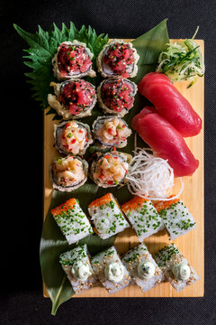 Sushi and sashimi served on nicely decorated wooden plate.