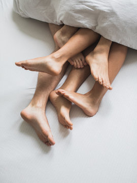 Three pairs of legs sticking from under the blanket