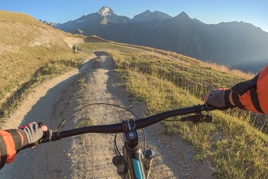 Mountain bike handlebar controlled by biker riding in on sunny trail