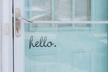 Front door painted turquoise blue with word hello