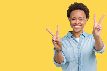 Young beautiful african american woman over isolated background smiling looking to the camera showing fingers doing victory sign. Number two.