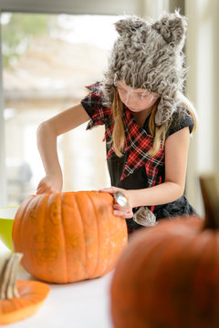Girl scooping out inside of a pumpkin