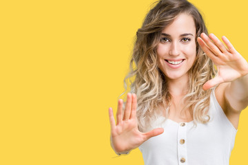 Beautiful young blonde woman over isolated background Smiling doing frame using hands palms and fingers, camera perspective